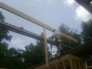 Carpenter setting a ridge beam over a new addition frame — Ice Dam Removal by Roofing Brothers in Graytown