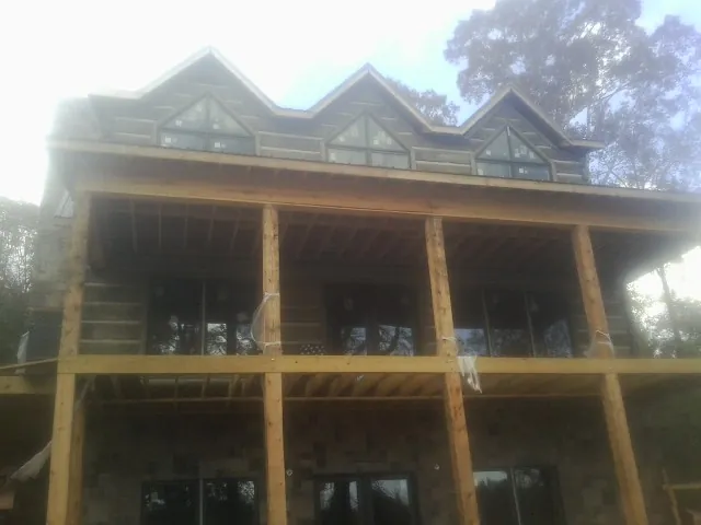 Dormers and porch framing on a large log home under construction — Roof Coating work by our crew in Graytown