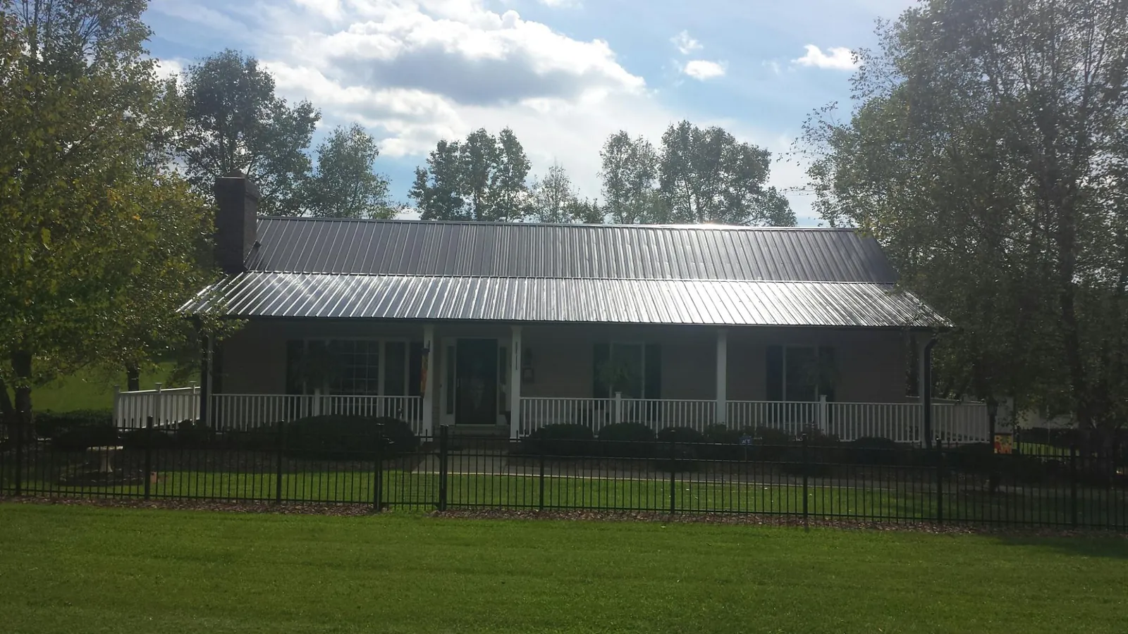 Gray metal roof on a brick ranch with a full width front porch — Gutter Guard Installation work by our crew in Graytown